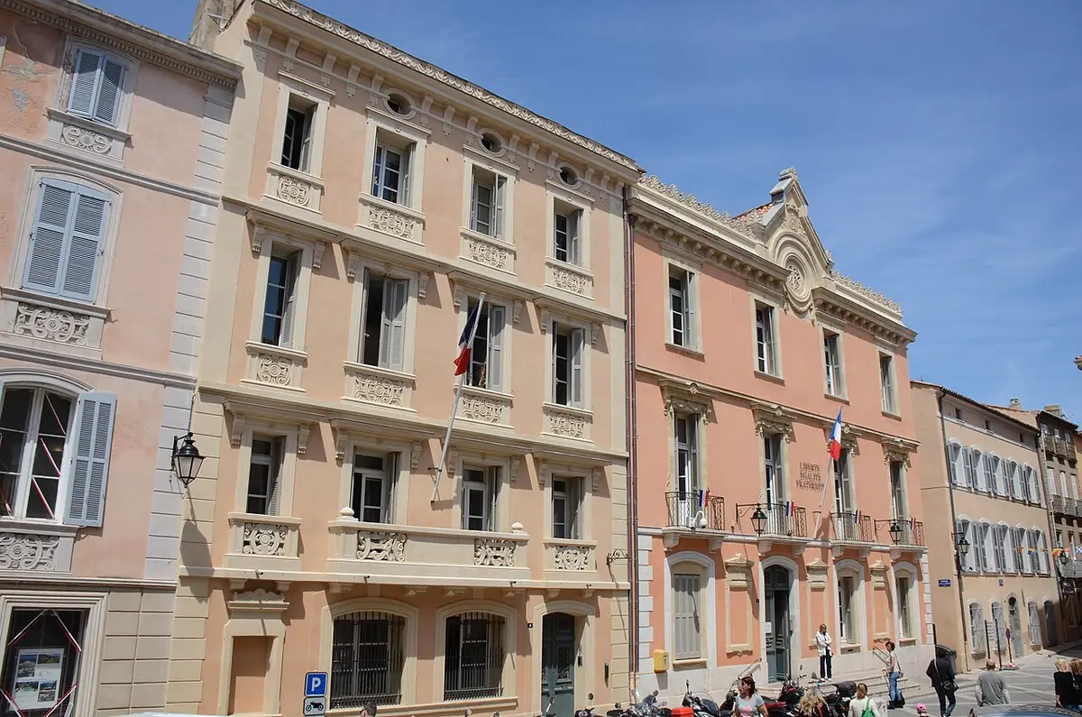 Façades roses et ocre de l’hôtel de ville de Saint-Tropez le long d’une rue