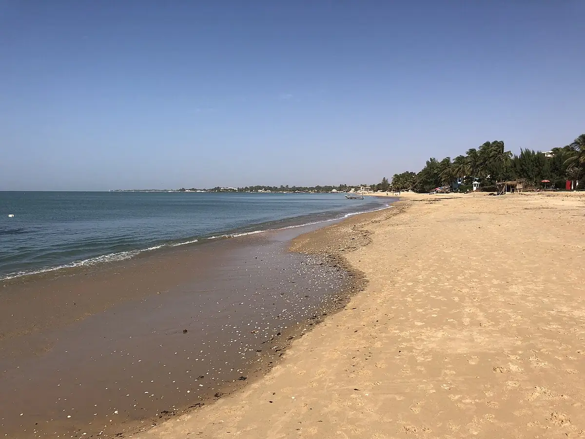 Longue plage de sable de Saly Portudal bordée d’arbres, mer calme