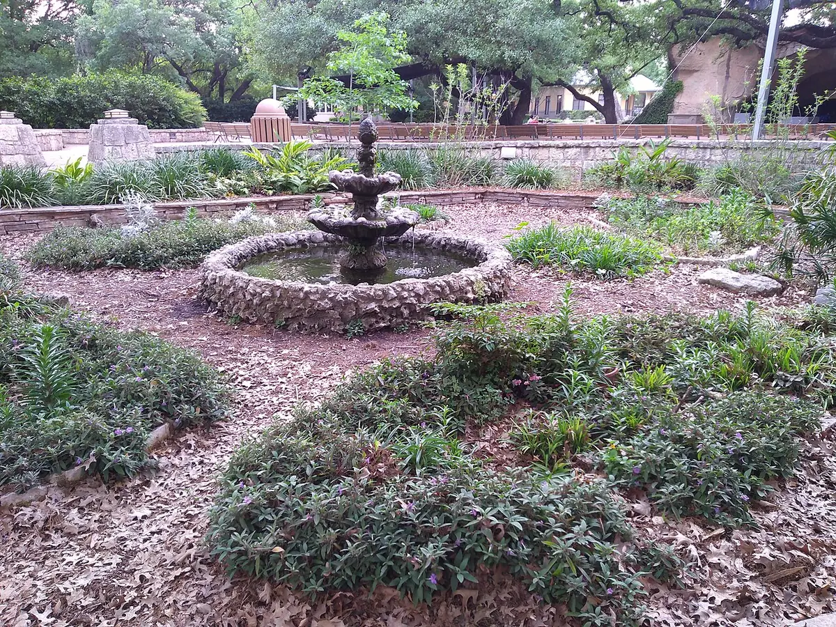 Une fontaine en pierre et un jardin à la Grotte de Lourdes à San Antonio