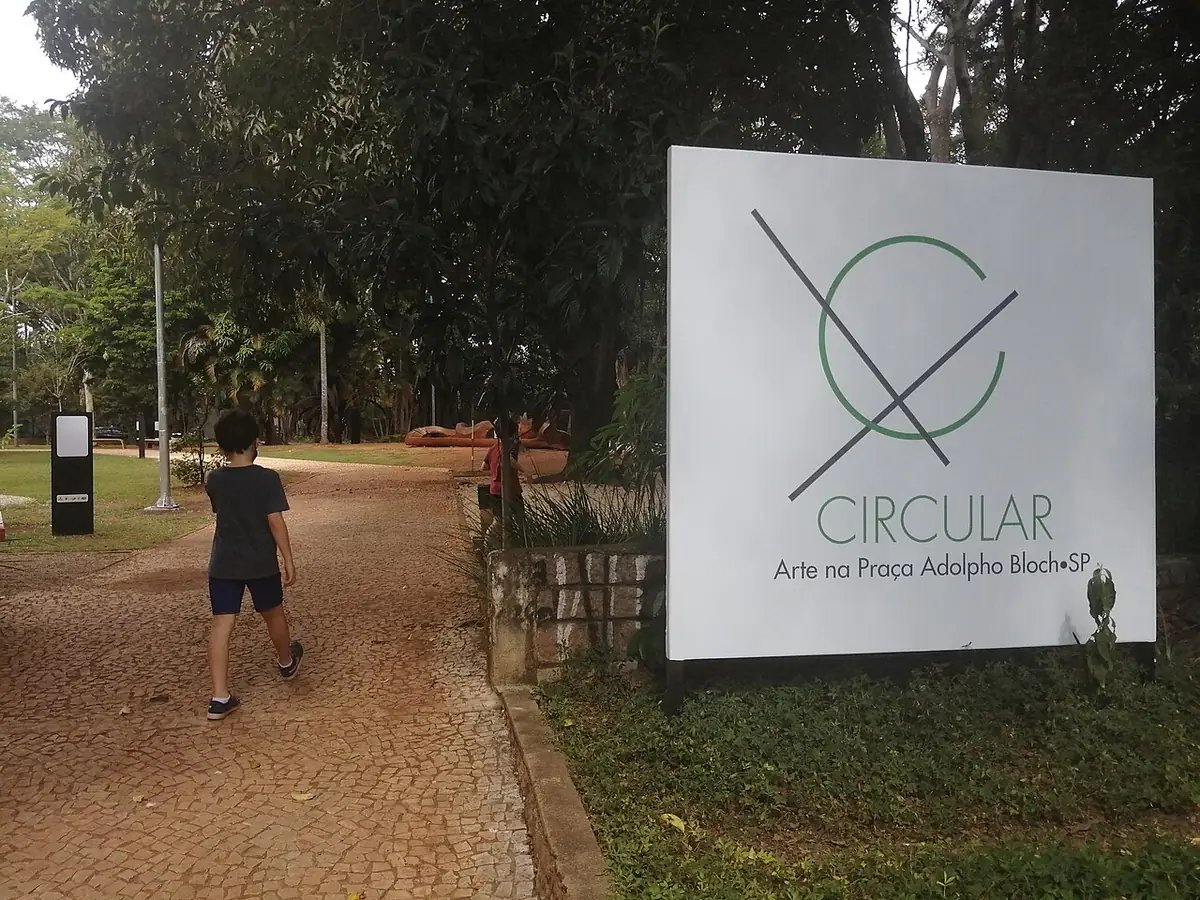 Une allée de la Praça Adolpho Bloch, avec un panneau du projet artistique du parc