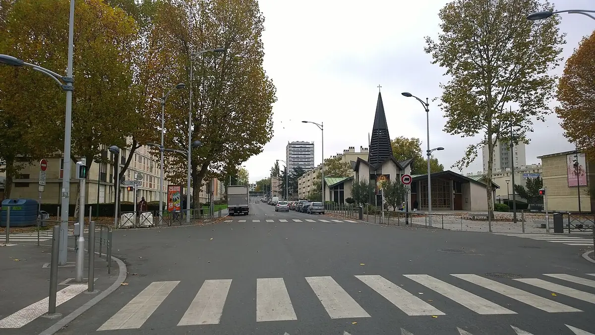 Large avenue de Sarcelles avec passage piéton, arbres et clocher au loin