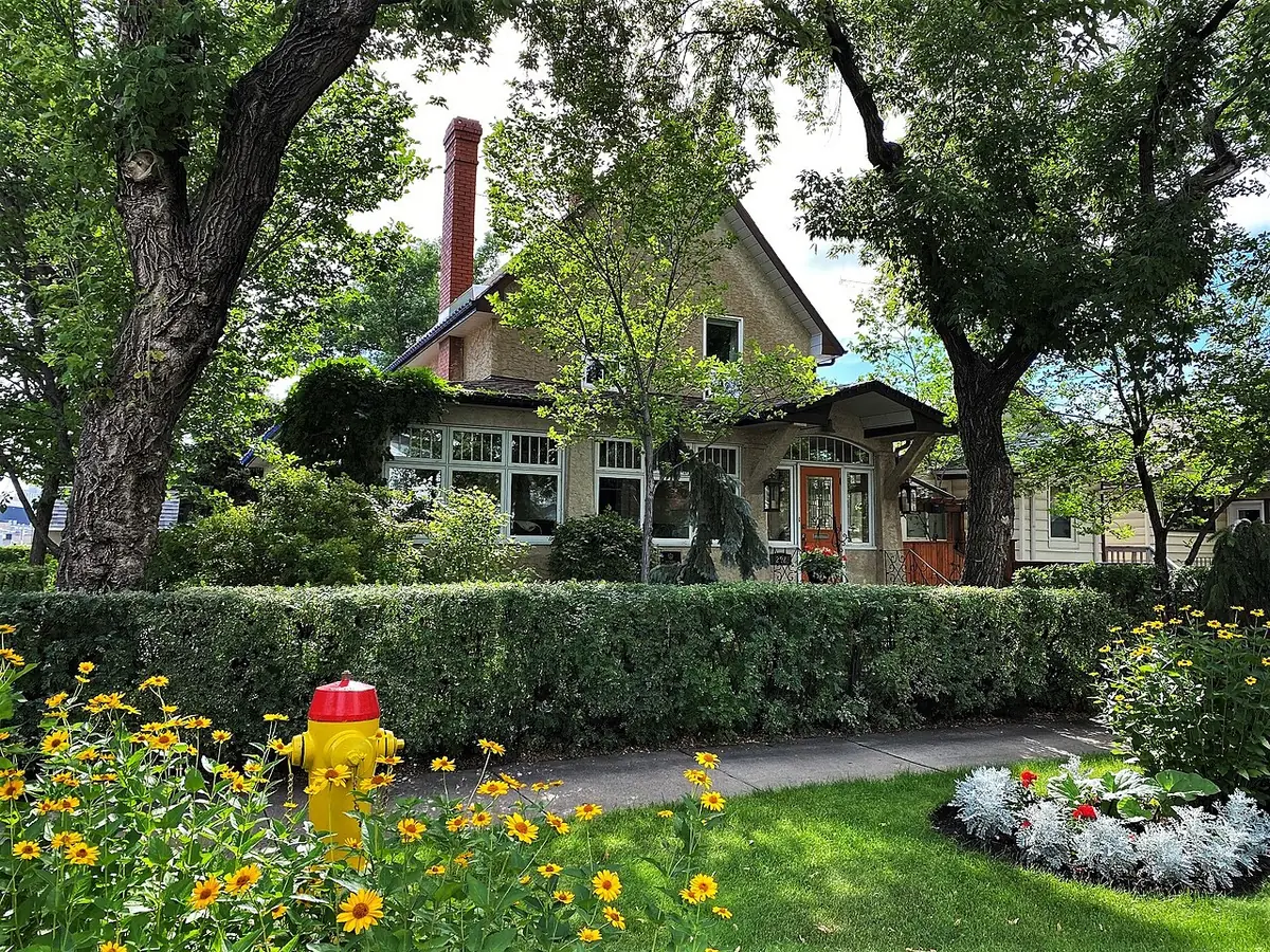 La Landa Residence à Saskatoon, maison entourée d’arbres, d’une haie et d’un jardin fleuri