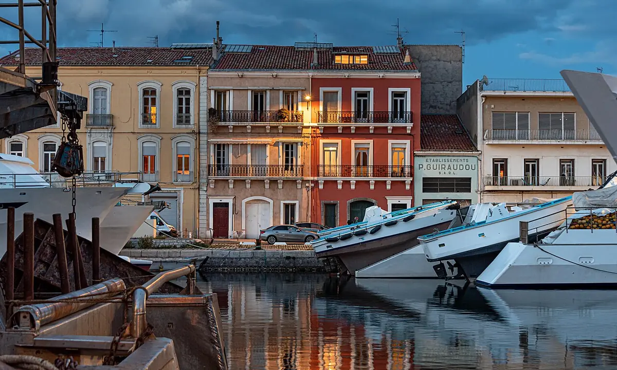 Immeubles aux façades colorées sur le quai, bateaux amarrés, à l’heure bleue