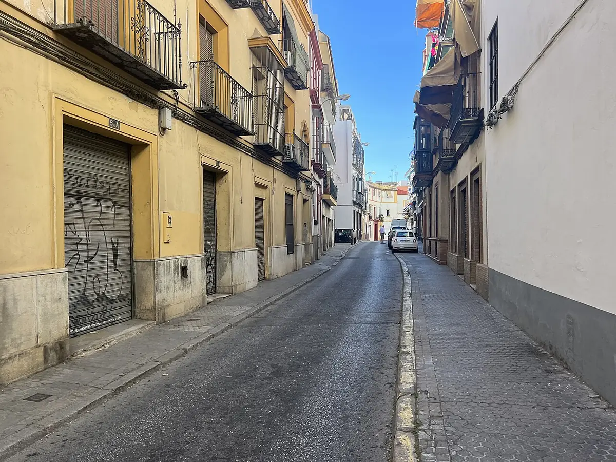 Rue étroite et vide de Séville bordée de façades jaunes et blanches à balcons