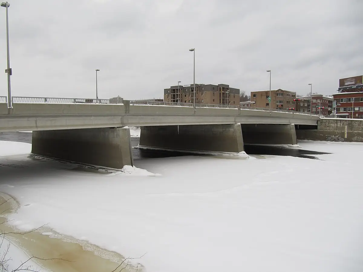 Le pont Aylmer sur la rivière Saint-François gelée et enneigée, immeubles résidentiels à l’arrière-plan