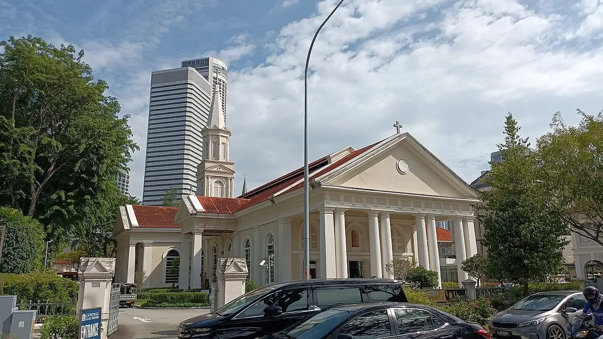 Une église blanche de style colonial au clocher élancé, devant un gratte-ciel moderne, à Singapour