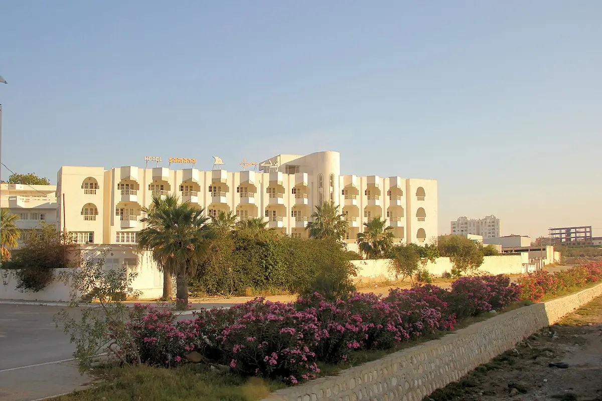 Un immeuble résidentiel blanc entouré de palmiers et de bougainvillées à Sousse