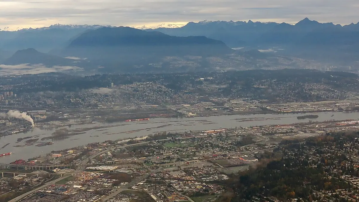 Vue aérienne du fleuve Fraser à Surrey, montagnes enneigées à l’horizon