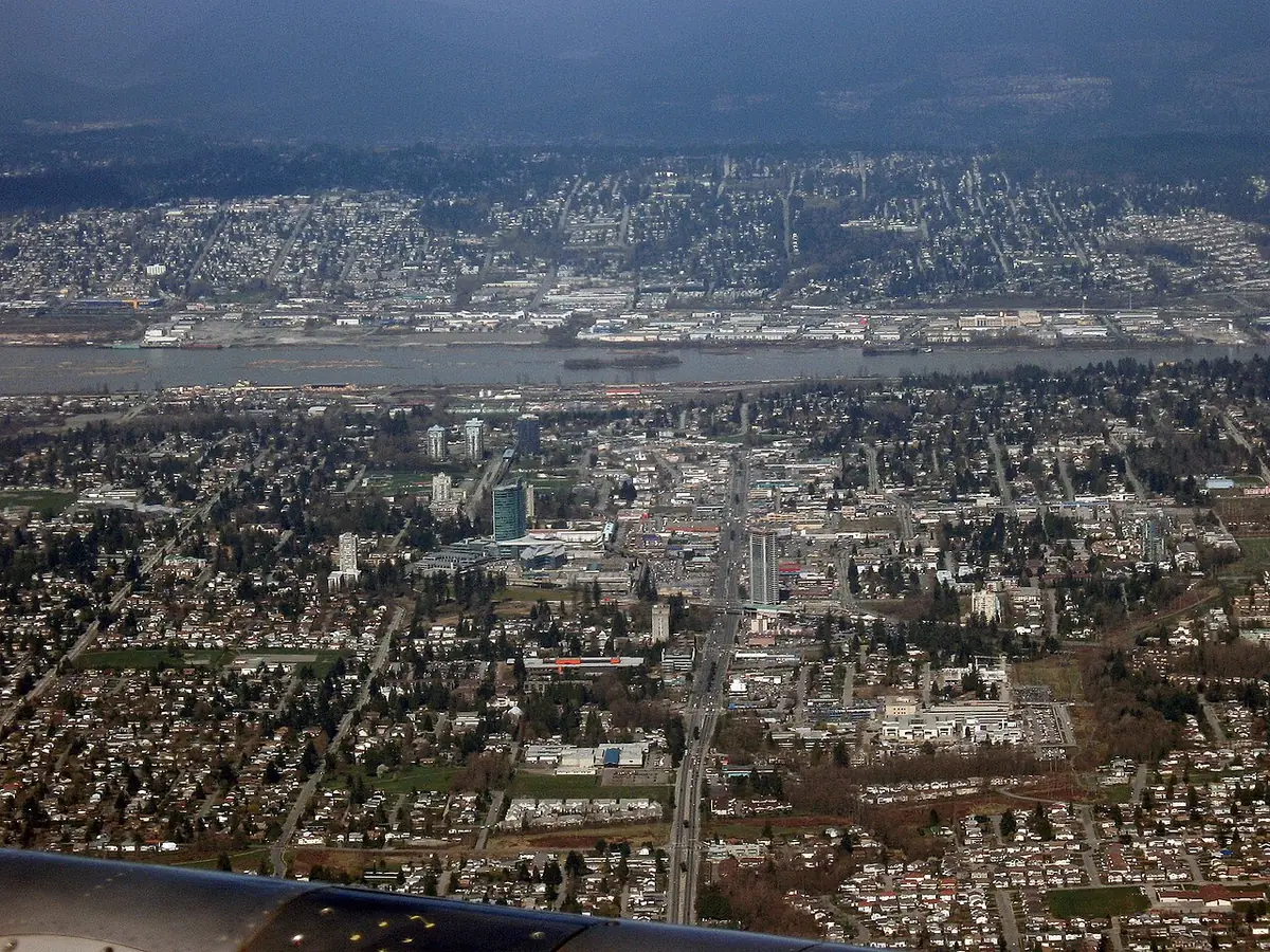 Vue aérienne de Surrey, quartiers résidentiels étendus jusqu’au fleuve, montagnes au loin