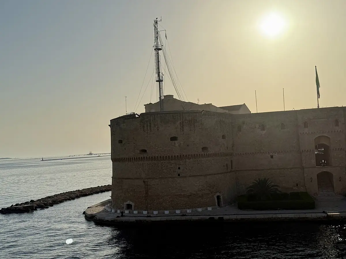Le Castello Aragonese de Tarente se reflétant dans la mer au soleil couchant