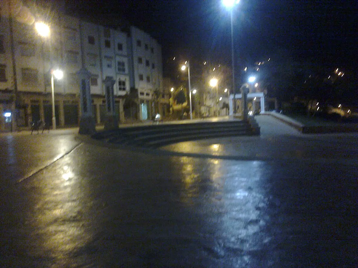 Une rue de Tétouan luisante de pluie, éclairée par les lampadaires le soir