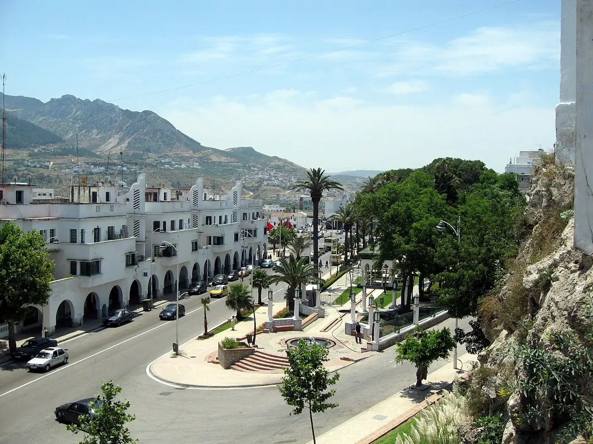 Une avenue à arcades bordée de palmiers, montagnes en arrière-plan à Tétouan
