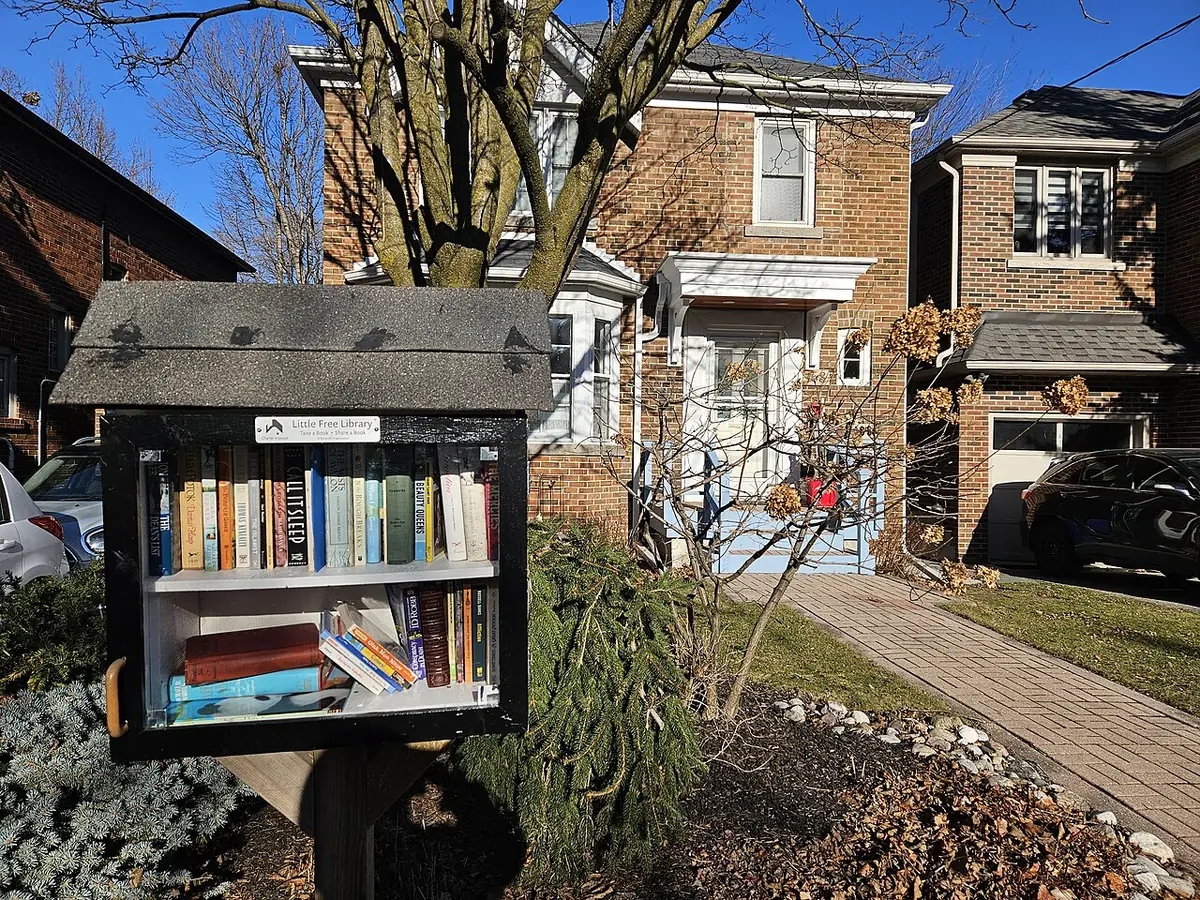 Une rue résidentielle de Toronto avec une petite bibliothèque libre devant une maison