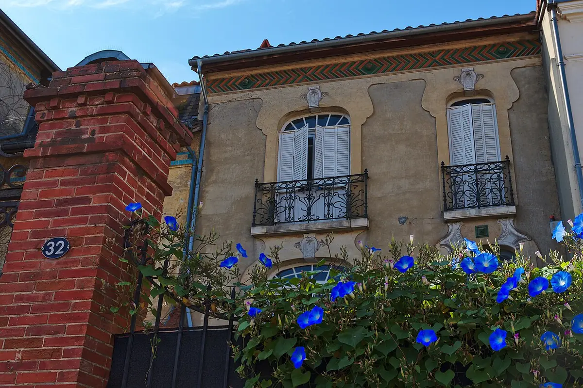 Une maison toulousaine en briques roses, balcons fleuris de fleurs bleues