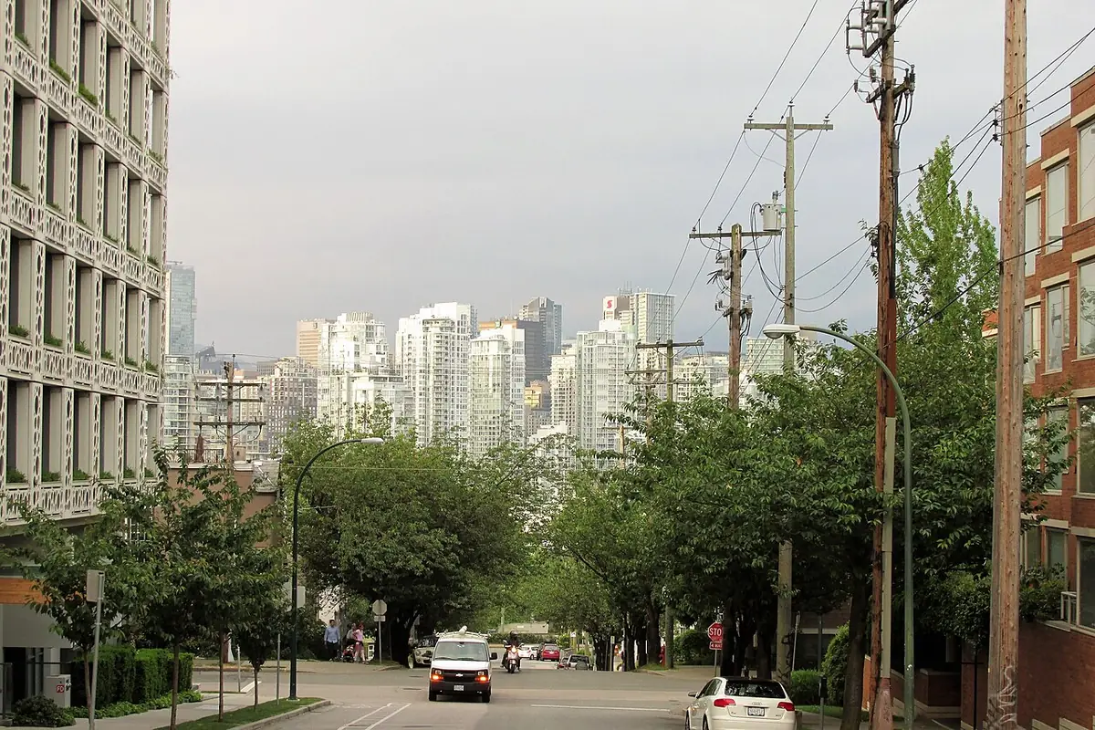 Une rue résidentielle de Vancouver bordée d’arbres, avec le centre-ville en arrière-plan