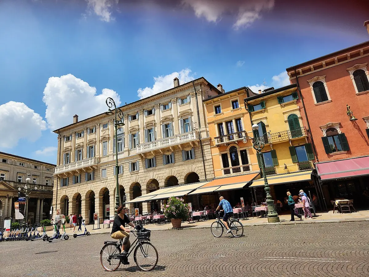 Une place animée de Vérone, entre façades colorées et cyclistes