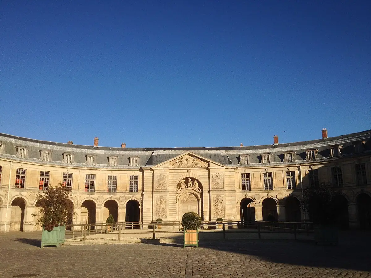 La façade classique en arc de cercle de la Grande Écurie de Versailles sous un ciel bleu