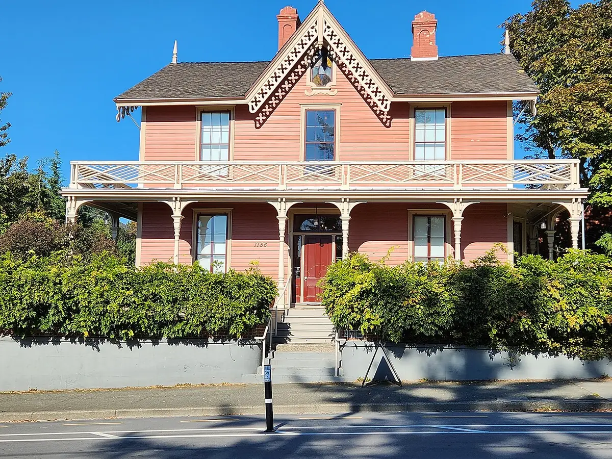 Une maison victorienne rose à balcons dans une rue de Victoria