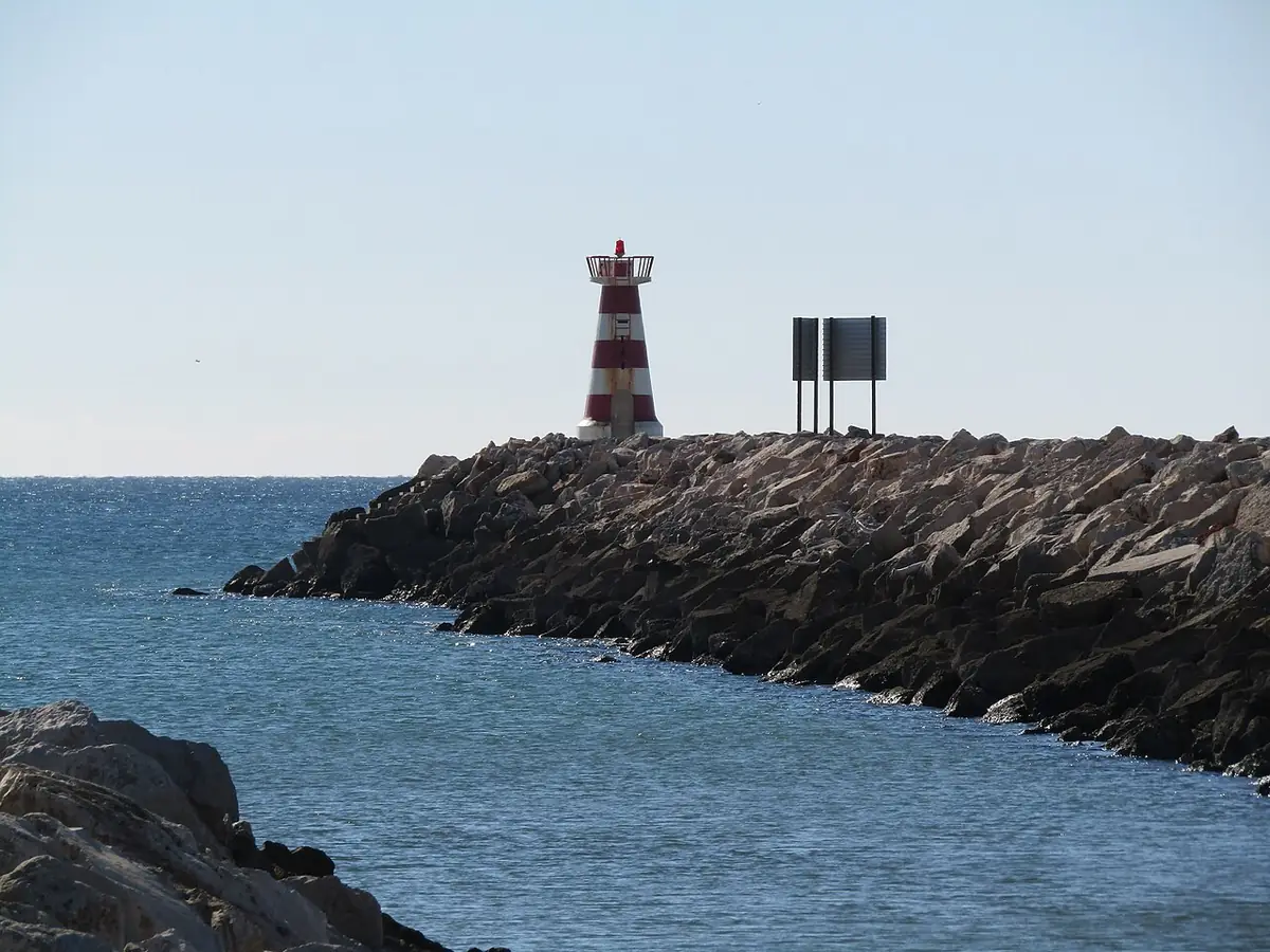 Phare rouge et blanc au bout de la digue ouest de Vilamoura, face à l’océan