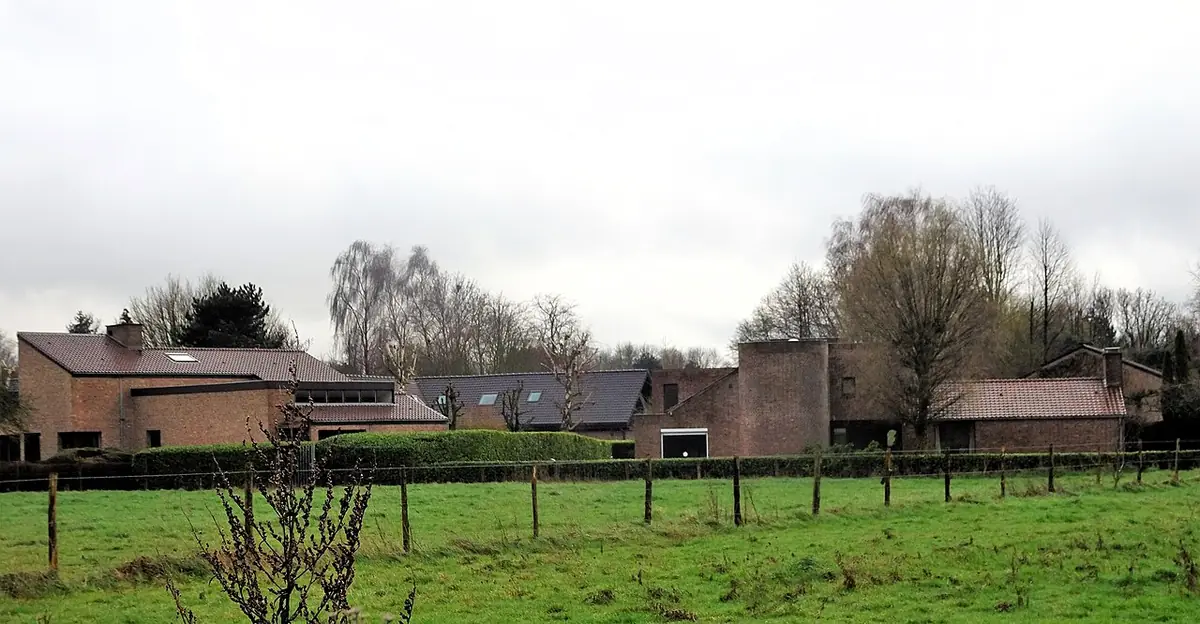 Maisons en brique du quartier de Brigode derrière une prairie clôturée