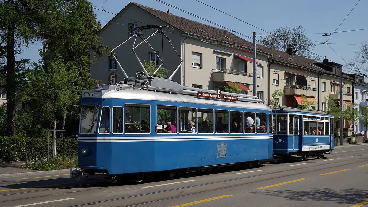 Un tramway bleu circulant dans une rue bordée d’immeubles à Zurich